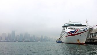 Cruise ship at pier in view of foggy city, Hong Kong, Victoria Harbour