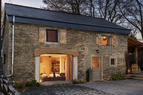 old stone House with open illuminated windows at evening