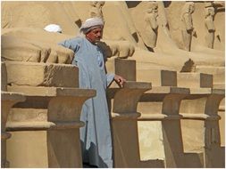 man among huge statues in a chrome complex in egypt
