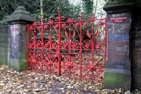 red painted wrought Iron Gate with graffitis to strawberry field at colorful fall, uk, england, liverpool