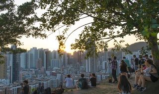 people photographing modern city from Hill at sunset