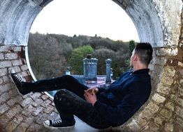 young man sits on a brick window