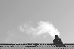 Black and white photo of the smoke from the chimney on the house