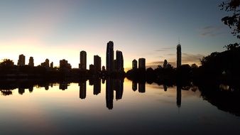 silhouettes of cityscape reflected in the water at dawn