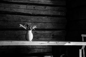 black and white photo of a vase with flowers on the table