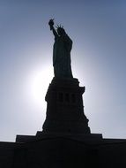 silhouette of Statue Of Liberty against the backdrop of the bright sun