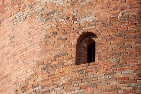 small arched Window in old red Brick Wall