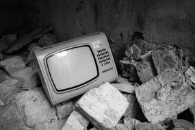 Black and white photo of the retro tv among the stones