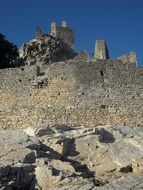 walls of medieval castle at blue sky background in Tuscany, Italy