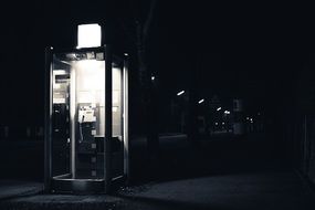 black and white photo of a telephone booth at night