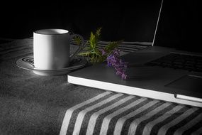 cup and flower near the laptop