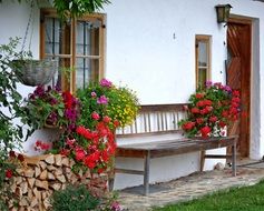 Bench decorated with flowers at old house Facade