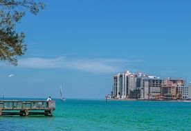 seascape with pier, sailing boat and buildings on coast, usa, florida, Sand Key Park