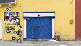 man walking along Old Colonial Building with blue gate, colombia, cartagena