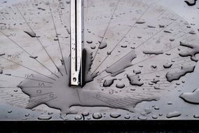 steel sundial in water drops