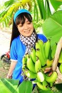 Vietnamese girl holds a branch of green bananas