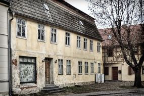 old house on the street next to a tree