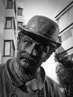 man in vintage hat, bronze sculpture in city