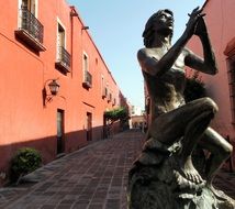 sculpture of a man with a flute on a city street