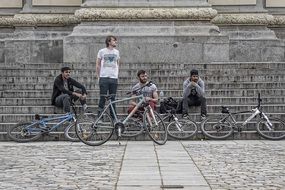 youth with bicycles near a building with large columns