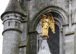 Golden angel statue and medieval church