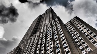 black and white photo of a skyscraper under the clouds