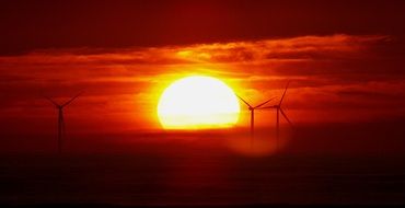 great bright sun in the sunset on the background of windmills