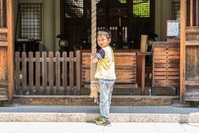 a boy stands near a wooden fence