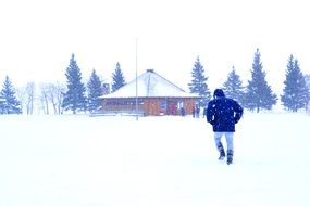 man walking on snow to house