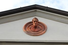 copper bust adorns the facade of the building