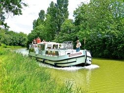 tourists in Boat on green Canal in wilderness