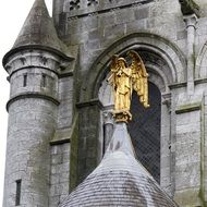 gold angel in front of catholic church in ireland