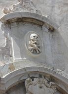 sculpture of a skull with bones on the facade of the building