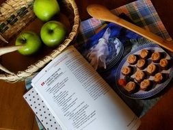 book with recipes and apples on the table