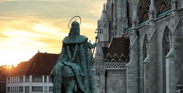 bronze statue in front of a gothic temple