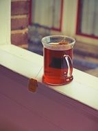 tea in a transparent cup on the windowsill