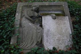 Beautiful tombstone among the plants in old cementery