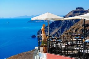 tables with chairs under umbrellas on the island of santorini