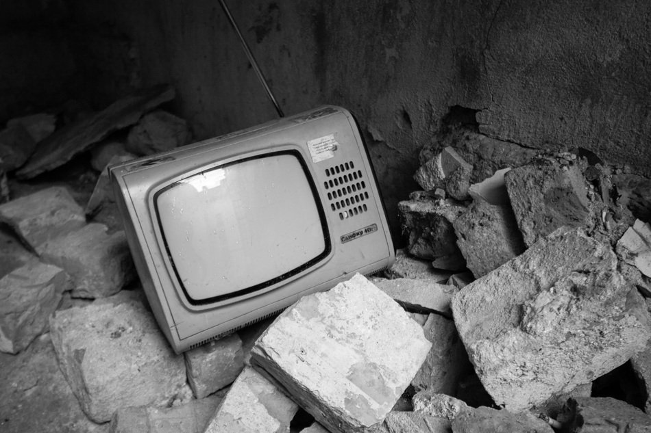 Black and white photo of the retro tv among the stones