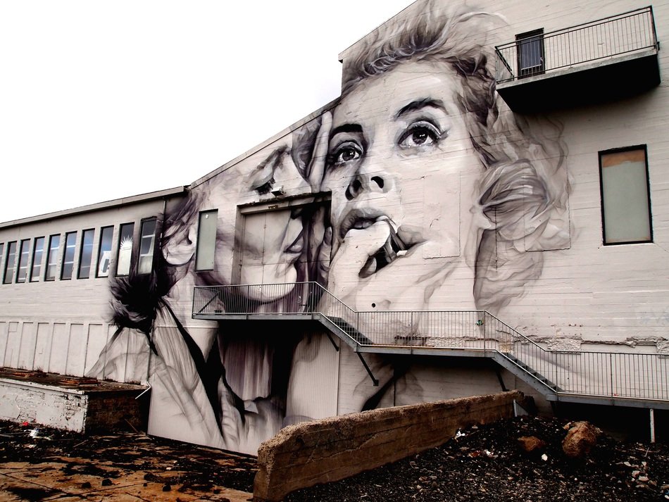 mural with female faces on the wall of an industrial building