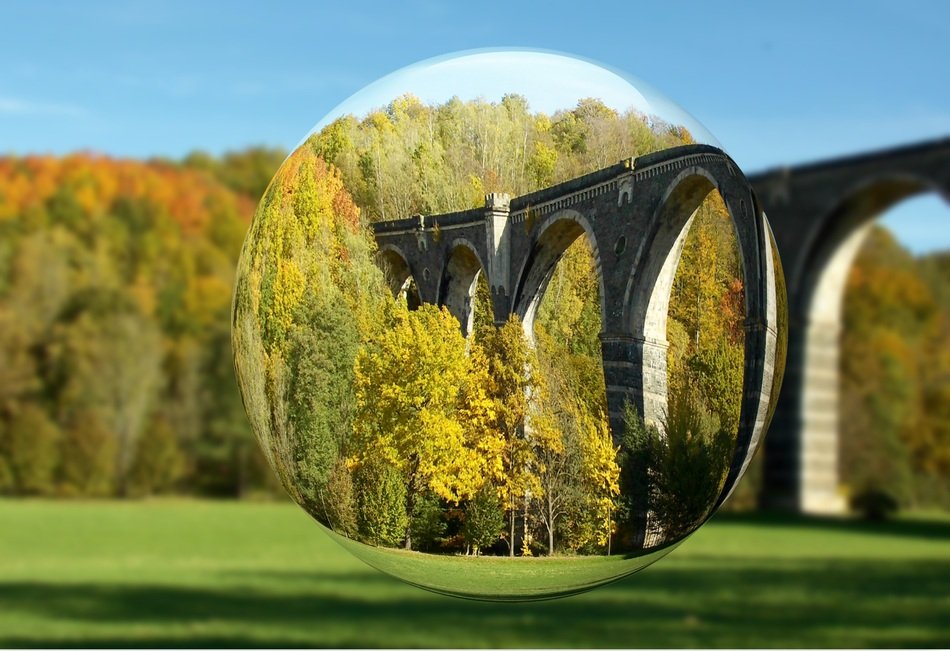 glass ball on a background of a bridge in green trees