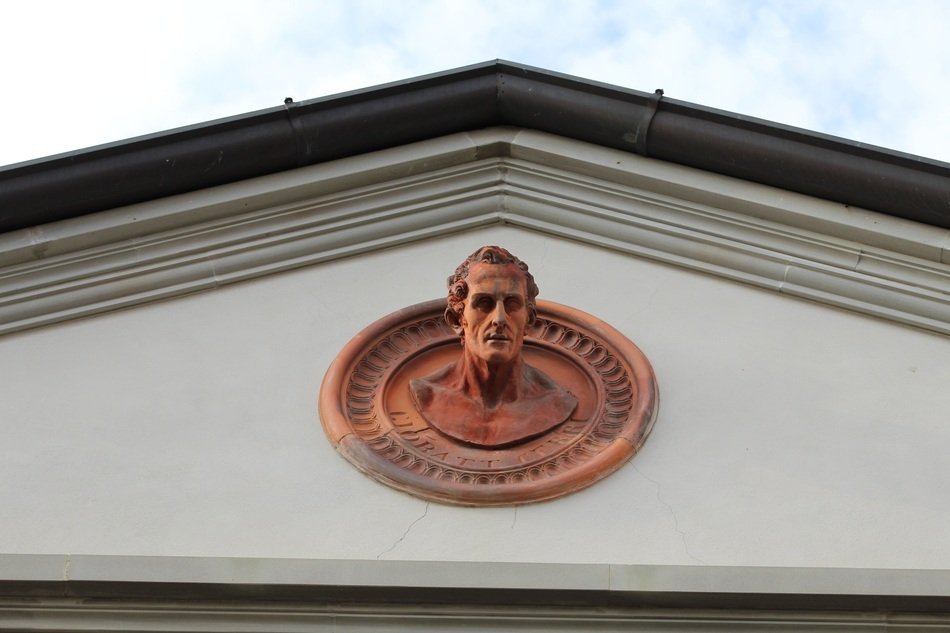 copper bust adorns the facade of the building