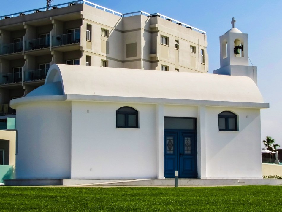 small white orthodox church with blue door on the green field