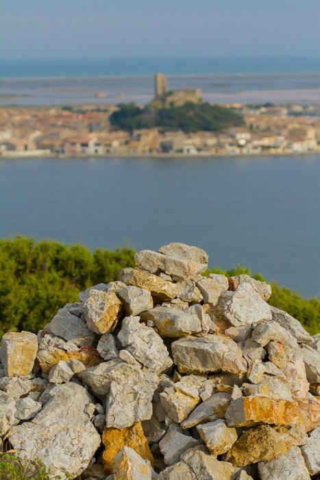 pile of wild Stones in front of distant barberousse tower, France, Gruissan