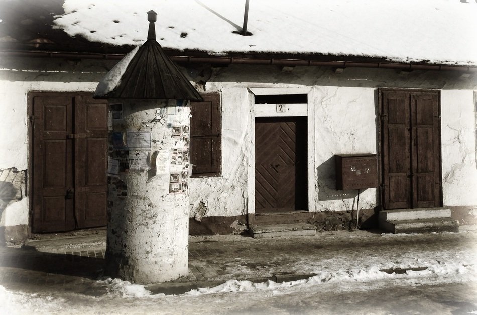 photo of an old one-story building and a post for announcements