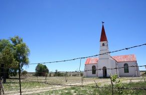 church with a spire behind barbed wire