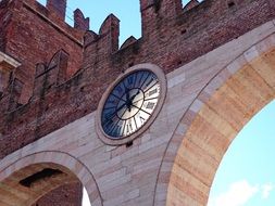 large clock on an arched building in verona