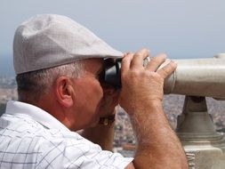 old man looking at city with telescope