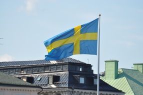 swedish flag waving above roofs