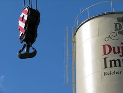 Crane Hook beside of industrial tank at sky